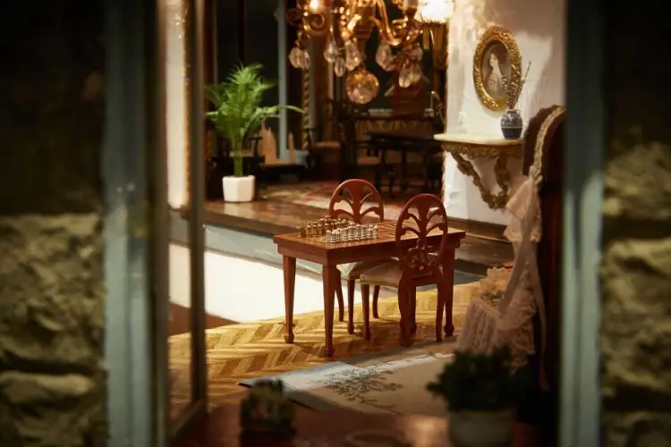 Study corner with a chess table, carved chairs, potted palm and hanging brass pans