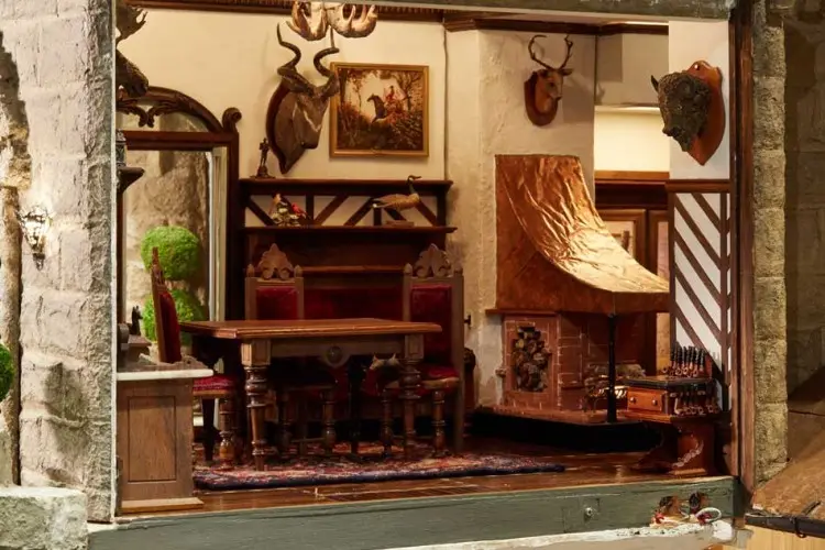Hunting lodge dining room with mounted antlers, a carved sideboard and a leather wingback chair