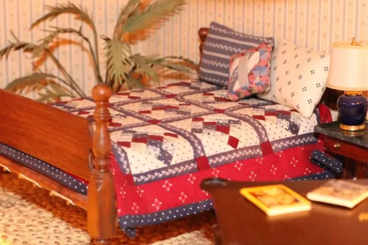 Guest bedroom with a patchwork quilt, turned bedposts and a bedside lamp