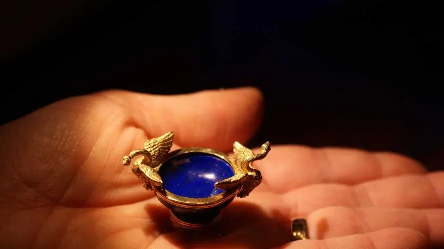 Tiny gilded bowl with a blue enamel lining, held in the palm of a hand