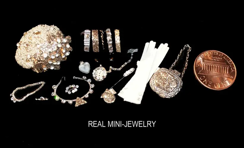 Miniature jewellery from the collection, including necklaces, gloves and a mesh purse, beside a penny